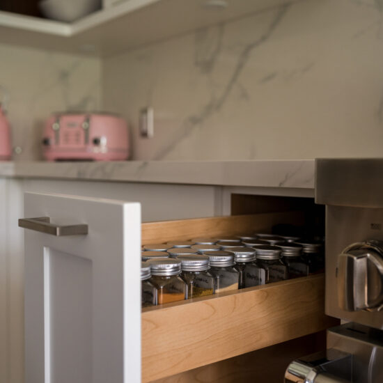Organized spice drawer in an Oshawa kitchen featuring custom wood inserts, sleek white cabinetry, and a marble backsplash for a functional and stylish design.
