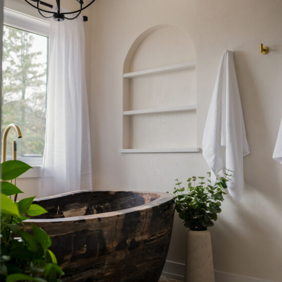 Elegant bathroom featuring a unique wooden bathtub, soft natural light, and a minimalist arched niche, designed for a tranquil retreat in Whitby