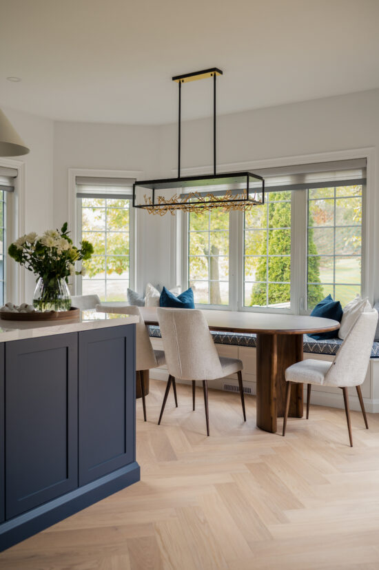 Bright, contemporary dining space featuring a wooden table, upholstered chairs, built-in window seating, and modern lighting, designed by MM Interior Design serving Whitby, Oshawa, and Clarington.