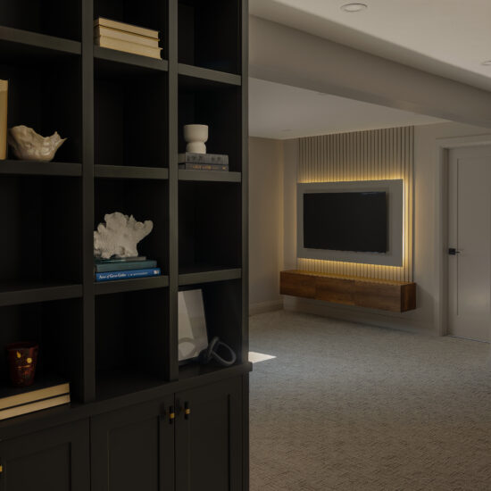 Stylish basement with custom built-in shelving and a floating TV console with backlit paneling in Ajax.